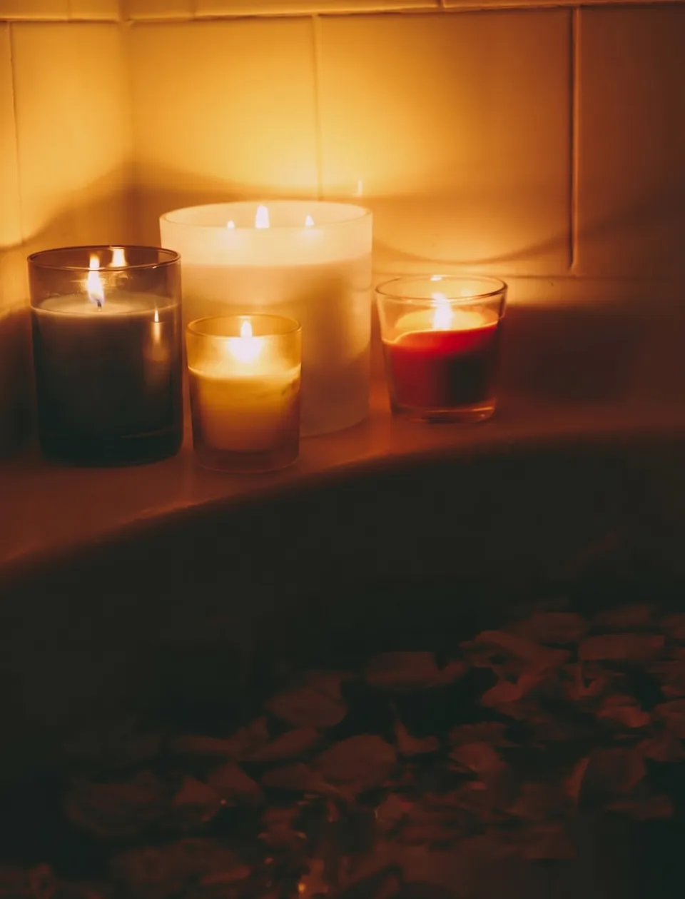 A bath drawn at the end of the day, with candles lit beside the tub.