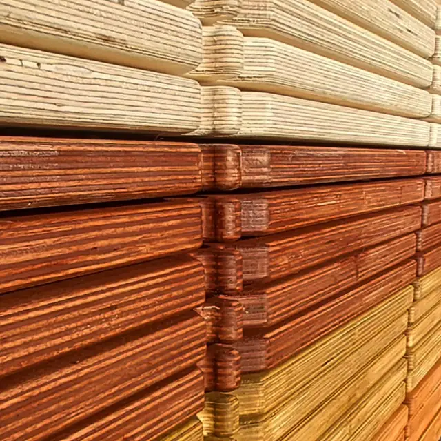 Finished bath boards stacked and seen end-on, the cross-ply birch layers showing in pale, cognac and havana finishes.