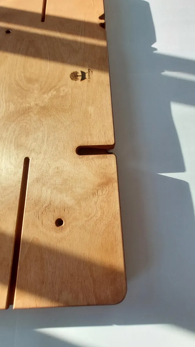 Low sunlight rakes across the top face of a board, picking out the routed groove, the stepped shoulder at its end, and the small branded Waverley mark.