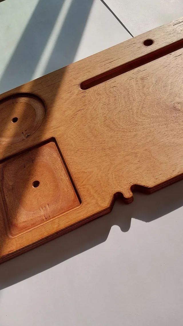An angled view of a dark-stained board: the recessed square tray and the round candle seat, with the shaped profile of the board’s edge running past them.
